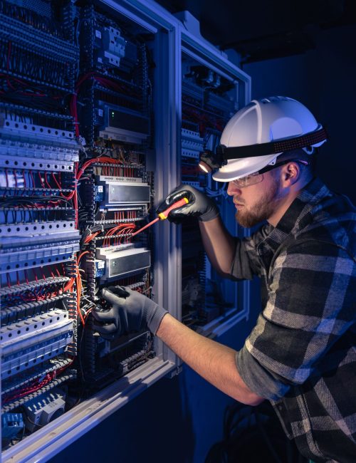 male-electrician-works-switchboard-overalls-against-backdrop-emergency-lighting (1)-min